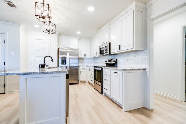 kitchen featuring sink, stainless steel appliances, white cabinets, and a center island with sink