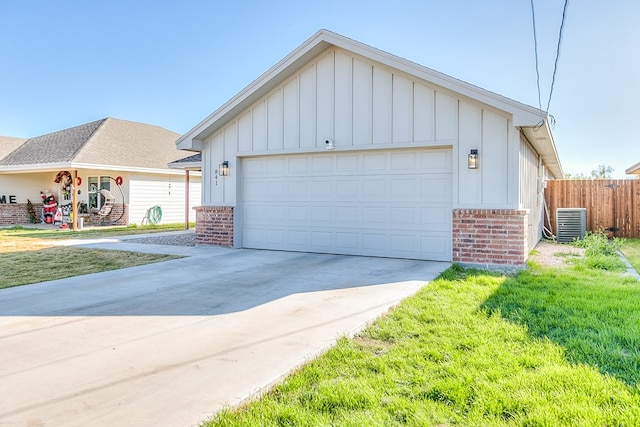 view of front of home with central AC unit, a garage, an outdoor structure, and a front yard