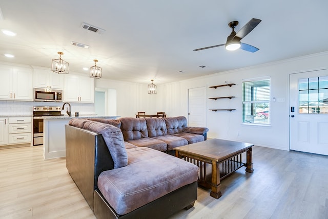 living room featuring crown molding, ceiling fan with notable chandelier, and light hardwood / wood-style flooring