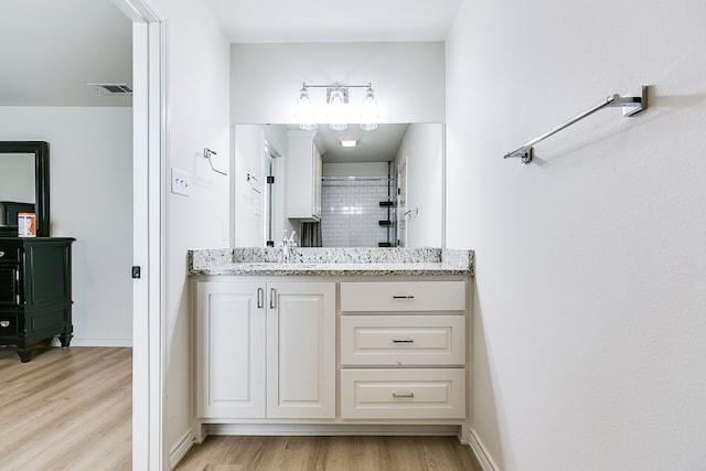 bathroom featuring vanity, wood-type flooring, and tiled shower