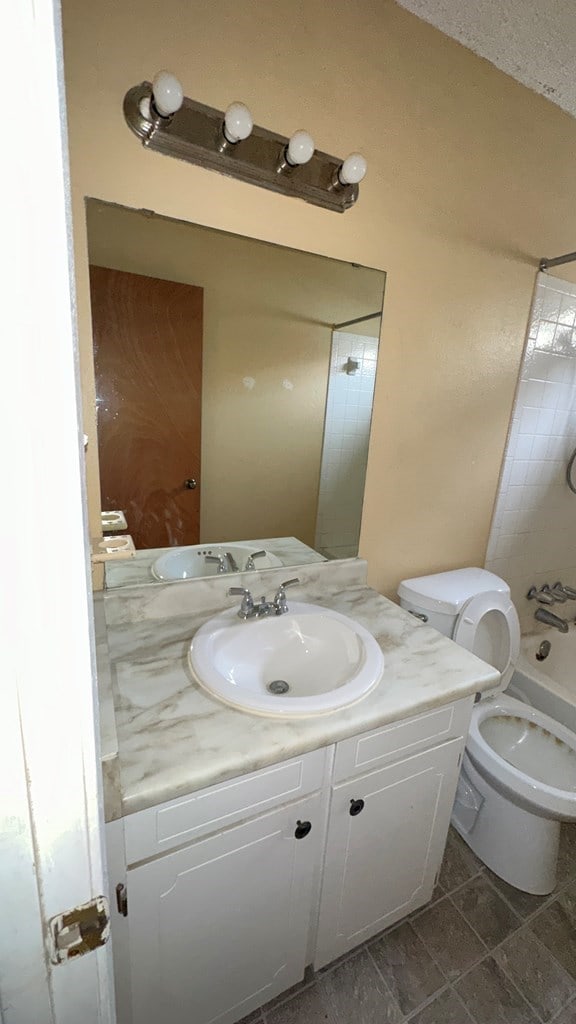 full bathroom featuring vanity,  shower combination, and toilet