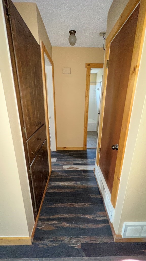 hallway with dark wood-type flooring and a textured ceiling