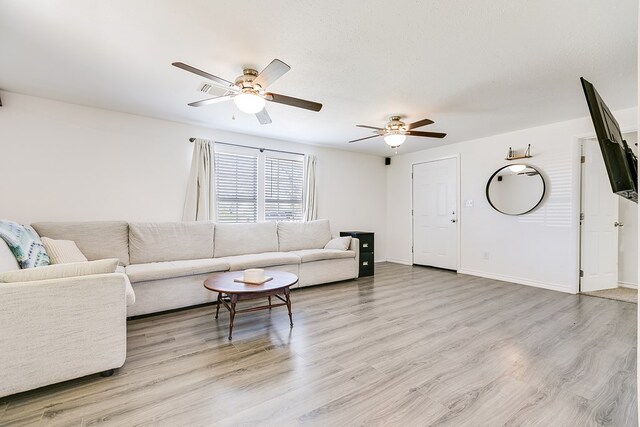 living room featuring a textured ceiling, light hardwood / wood-style flooring, and ceiling fan