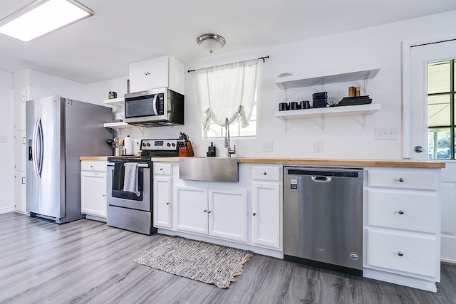 kitchen featuring appliances with stainless steel finishes, sink, white cabinets, and light hardwood / wood-style floors