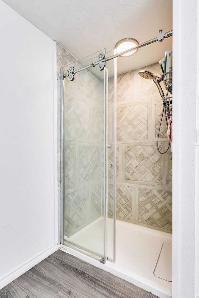 bathroom with hardwood / wood-style floors, a textured ceiling, and walk in shower