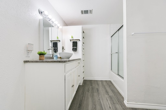 bathroom with hardwood / wood-style flooring, enclosed tub / shower combo, and vanity