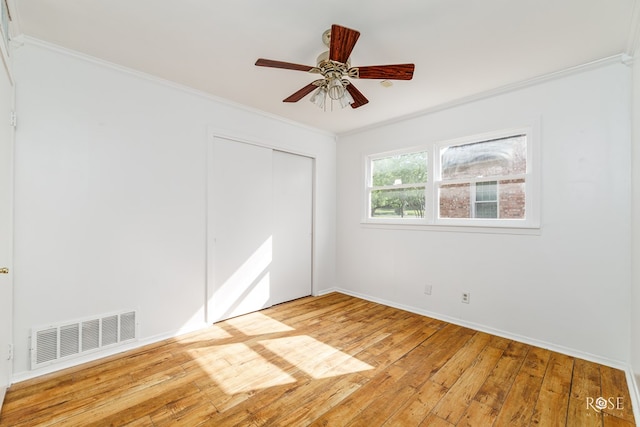unfurnished bedroom featuring crown molding, light wood-style floors, a closet, and visible vents
