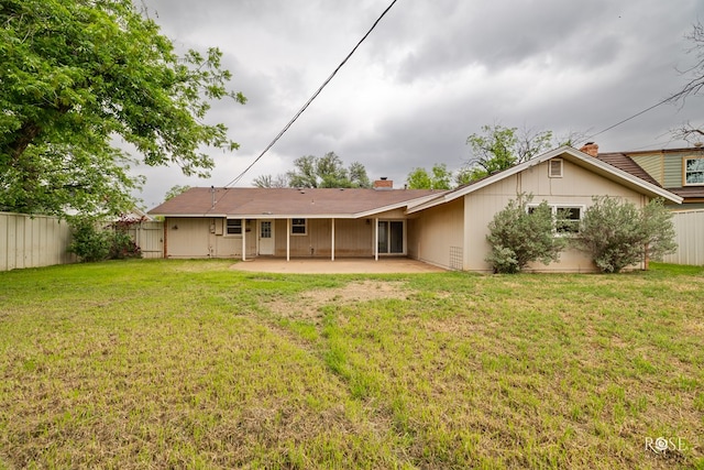 rear view of property featuring a chimney, a patio, fence, and a lawn