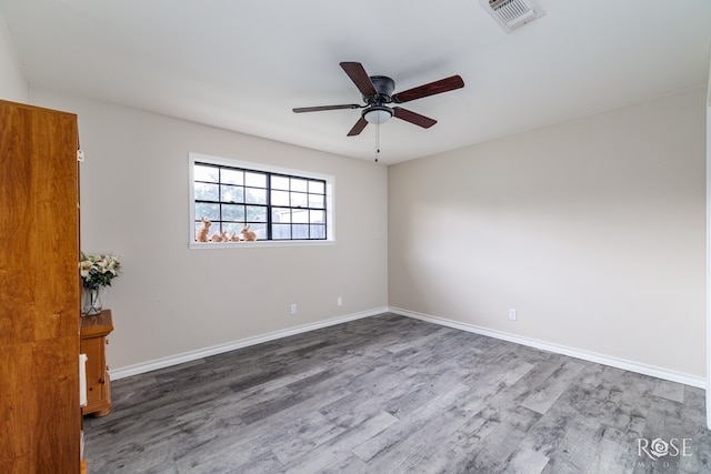 empty room featuring a ceiling fan, baseboards, visible vents, and wood finished floors