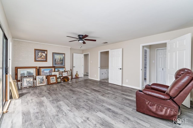 living area with baseboards, a ceiling fan, wood finished floors, and visible vents