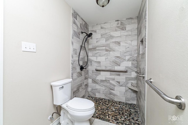 bathroom with toilet, tile patterned floors, and tiled shower
