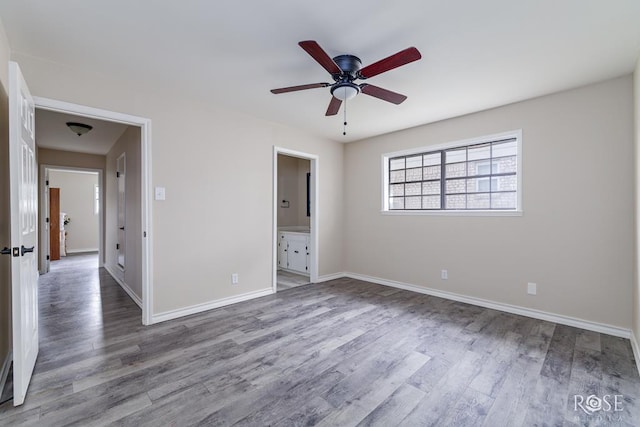 unfurnished bedroom featuring baseboards, ensuite bath, and wood finished floors