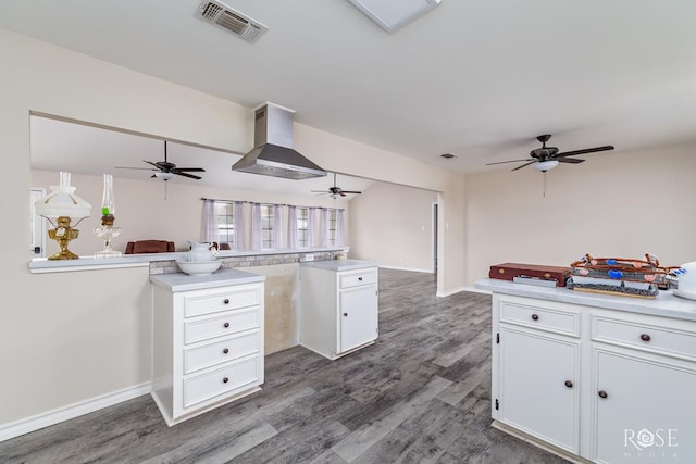 kitchen with visible vents, a peninsula, white cabinets, and ceiling fan
