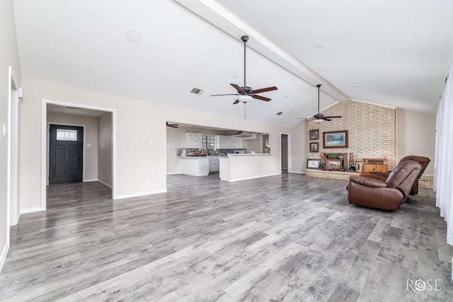living area with ceiling fan, visible vents, vaulted ceiling with beams, and wood finished floors