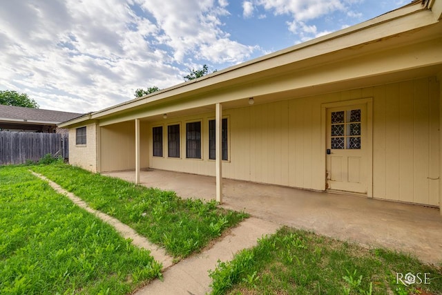 back of house featuring fence, a lawn, a patio area, and brick siding