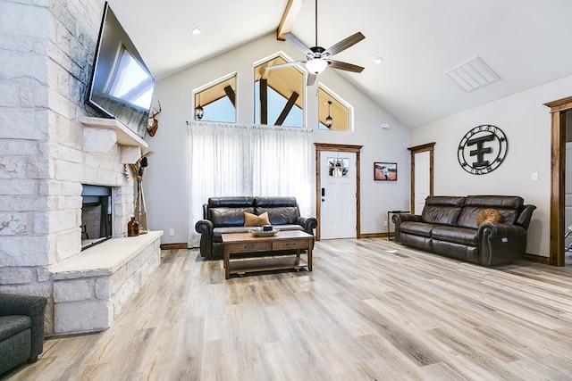 living room with high vaulted ceiling, light wood-type flooring, a stone fireplace, and a ceiling fan