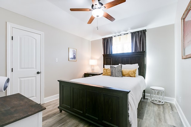 bedroom featuring ceiling fan, baseboards, and wood finished floors