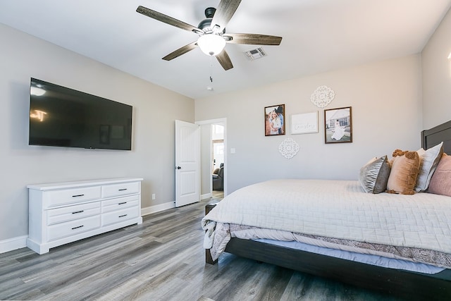 bedroom featuring a ceiling fan, visible vents, baseboards, and wood finished floors