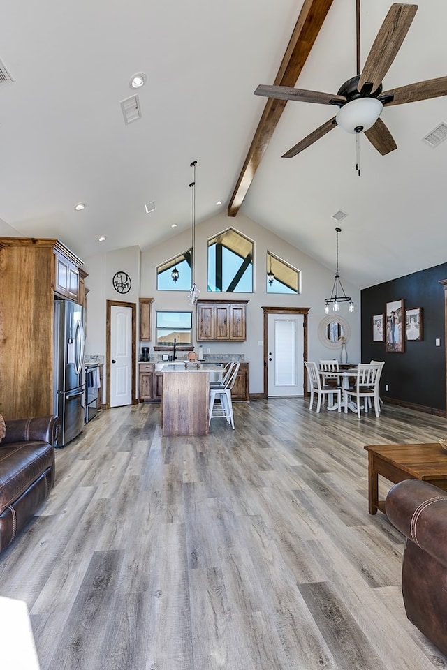 kitchen featuring pendant lighting, visible vents, brown cabinetry, open floor plan, and stainless steel fridge