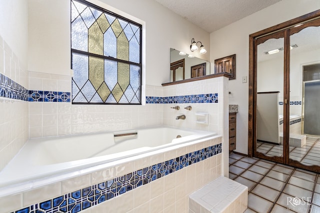 bathroom with a garden tub, a textured ceiling, and tile patterned floors