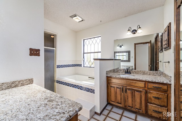 bathroom with a textured ceiling, a garden tub, visible vents, vanity, and a shower stall