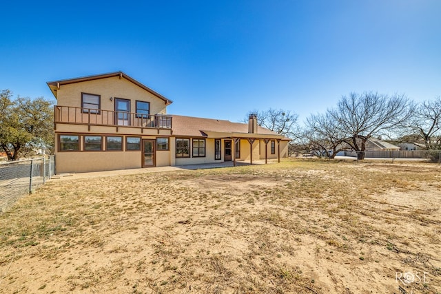 rear view of house with a balcony, fence, a patio, and stucco siding