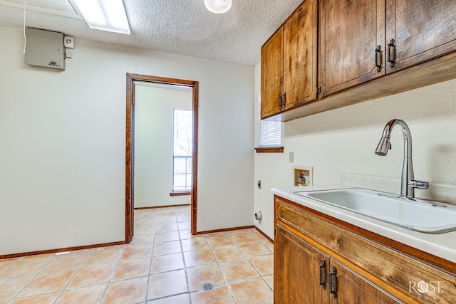 laundry room with cabinet space, a textured ceiling, hookup for an electric dryer, washer hookup, and a sink