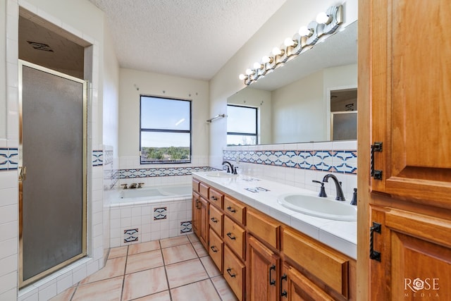 bathroom featuring a stall shower, a garden tub, a sink, and a textured ceiling