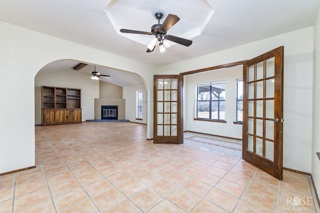 unfurnished living room featuring a large fireplace, light tile patterned floors, ceiling fan, vaulted ceiling, and french doors