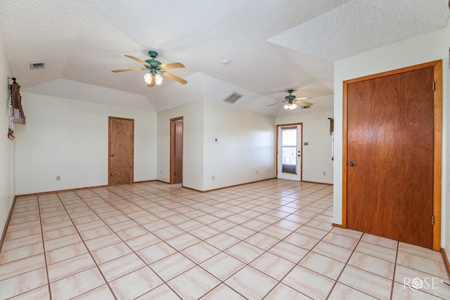 empty room with visible vents, vaulted ceiling, a textured ceiling, and light tile patterned floors