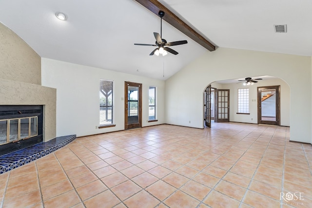 unfurnished living room with arched walkways, visible vents, a high end fireplace, light tile patterned flooring, and ceiling fan