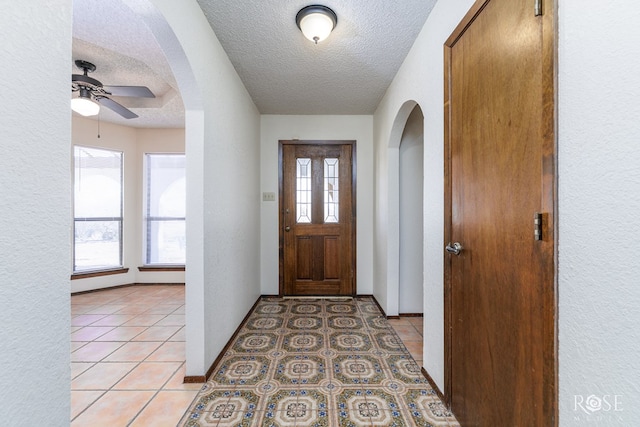 foyer entrance featuring light tile patterned floors, a textured ceiling, and a healthy amount of sunlight