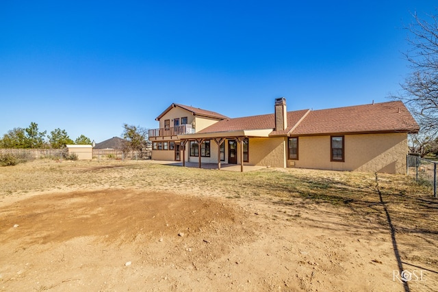 rear view of property featuring stucco siding, a patio, a chimney, and fence