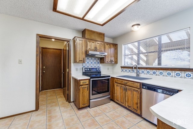 kitchen featuring stainless steel appliances, a sink, light countertops, and under cabinet range hood