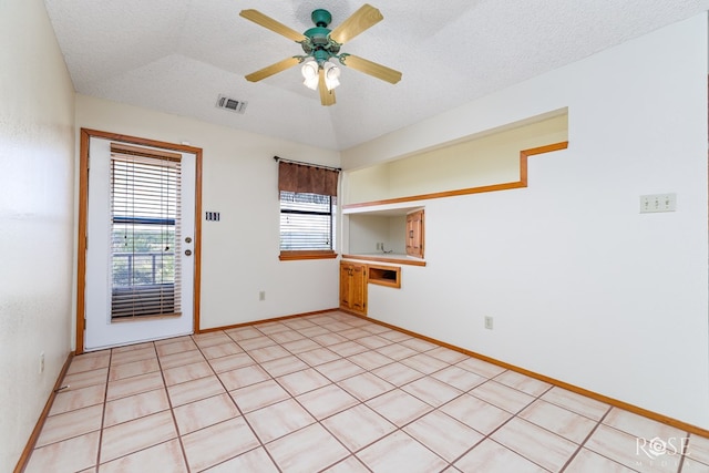 unfurnished room featuring baseboards, visible vents, ceiling fan, vaulted ceiling, and a textured ceiling