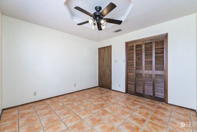 unfurnished bedroom with two closets, light tile patterned floors, visible vents, ceiling fan, and a textured ceiling