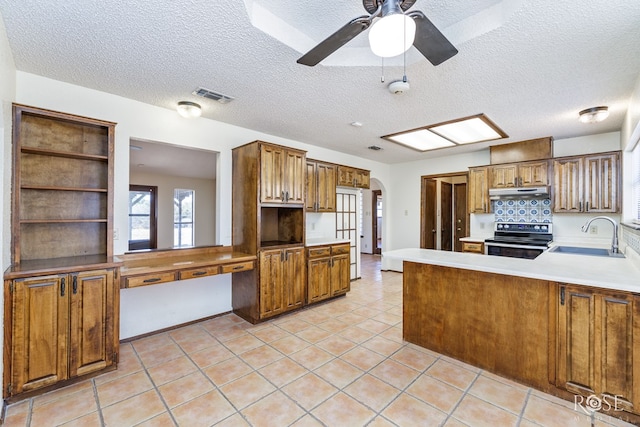 kitchen featuring visible vents, arched walkways, stainless steel electric stove, under cabinet range hood, and a sink