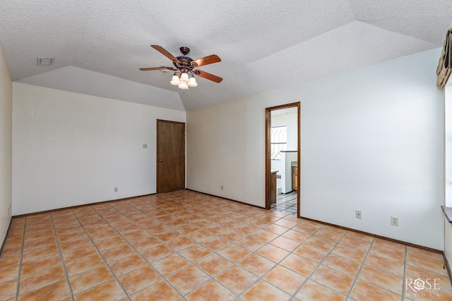 empty room featuring light tile patterned floors, ceiling fan, vaulted ceiling, and a textured ceiling