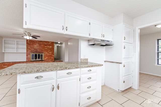2109 Dartmouth Dr, San Angelo, TX 76904 - kitchen with under cabinet range hood, light tile patterned floors, a textured ceiling, ceiling fan, and white cabinetry