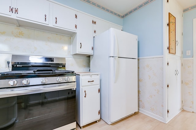 2650 Rice Ave, San Angelo, TX 76904 - kitchen with stainless steel range with gas cooktop, freestanding refrigerator, light countertops, white cabinetry, and wallpapered walls