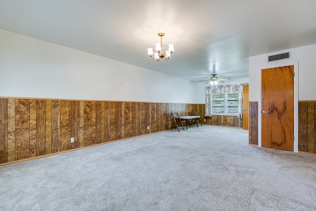 2650 Rice Ave, San Angelo, TX 76904 - empty room with a chandelier, wainscoting, a ceiling fan, carpet, and wooden walls