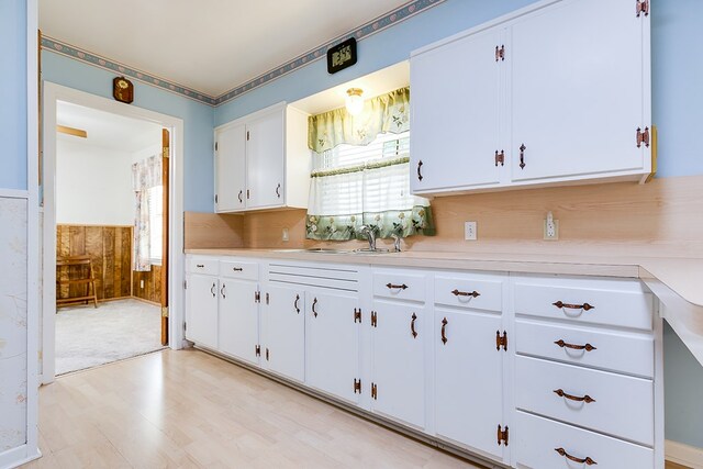 2650 Rice Ave, San Angelo, TX 76904 - kitchen with a sink, light countertops, wainscoting, light wood-style flooring, and white cabinets