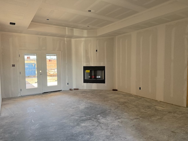 unfurnished living room with a glass covered fireplace, unfinished concrete flooring, and french doors