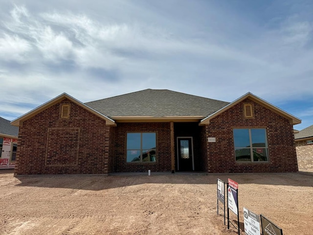 ranch-style home featuring brick siding and a shingled roof