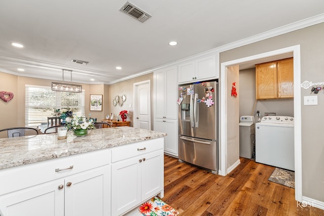 kitchen with light stone counters, stainless steel fridge, decorative light fixtures, and white cabinets