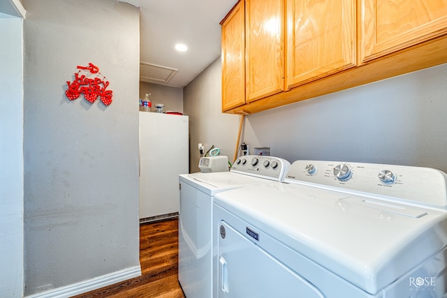 washroom with dark wood-type flooring, cabinets, and washer and clothes dryer