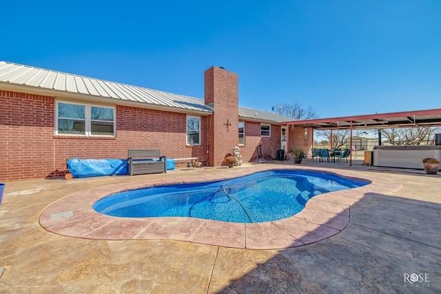 view of swimming pool featuring a hot tub and a patio