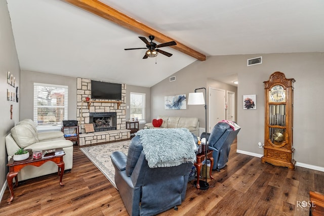 living room with dark wood-type flooring, ceiling fan, a stone fireplace, and lofted ceiling with beams