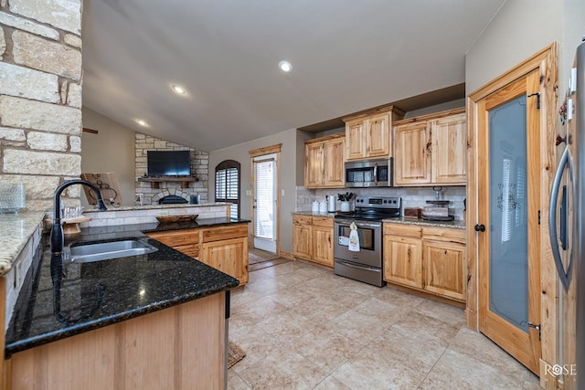 kitchen with stainless steel appliances, lofted ceiling, decorative backsplash, a sink, and dark stone counters