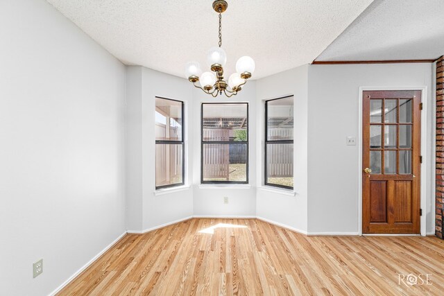 5821 Davenport Dr, San Angelo, TX 76901 - unfurnished dining area with a chandelier, light wood finished floors, a textured ceiling, and baseboards